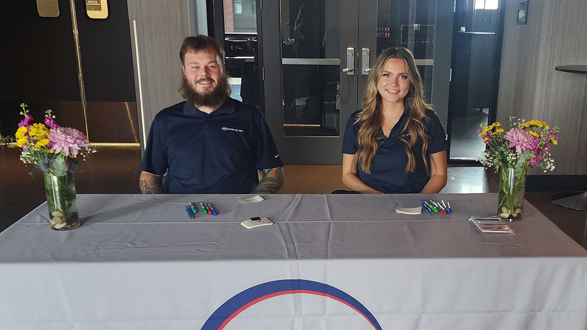 PE Systems interns seated at a greeting table