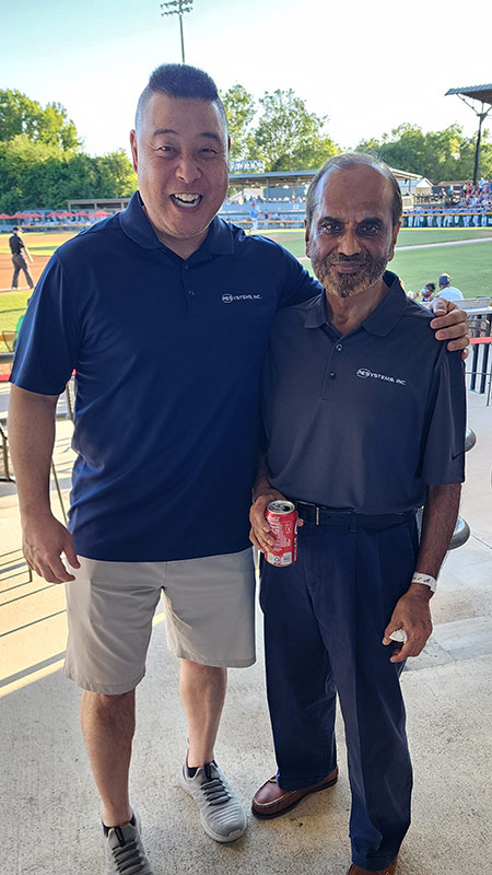 PE Systems employees smiling at a baseball game