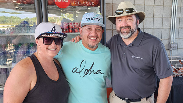 PE Systems employees smiling at a baseball game