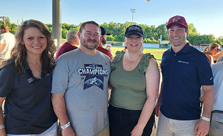 PE Systems employees smiling at a baseball game