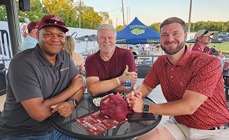 PE Systems employees smiling at a baseball game