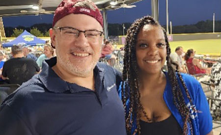 PE Systems employees smiling at a baseball game