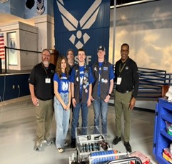 Robotics team posing with their robot at a STEM competition.